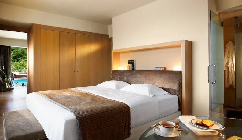 Doppelbett mit brauner Tagesdecke und integrierter Holz-Ablage mit Beleuchtung.