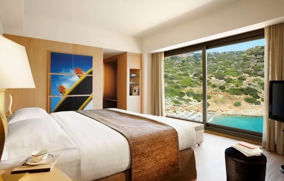 Modern eingerichtetes Schlafzimmer mit großem Doppelbett und Ausblick auf das Meer und die Bucht.