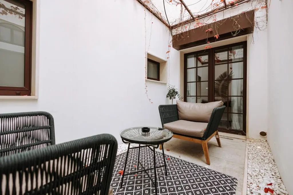 Terrasse im Innenhof mit modernen Sitzmöbeln, kleinem Tisch und gemustertem Teppich.