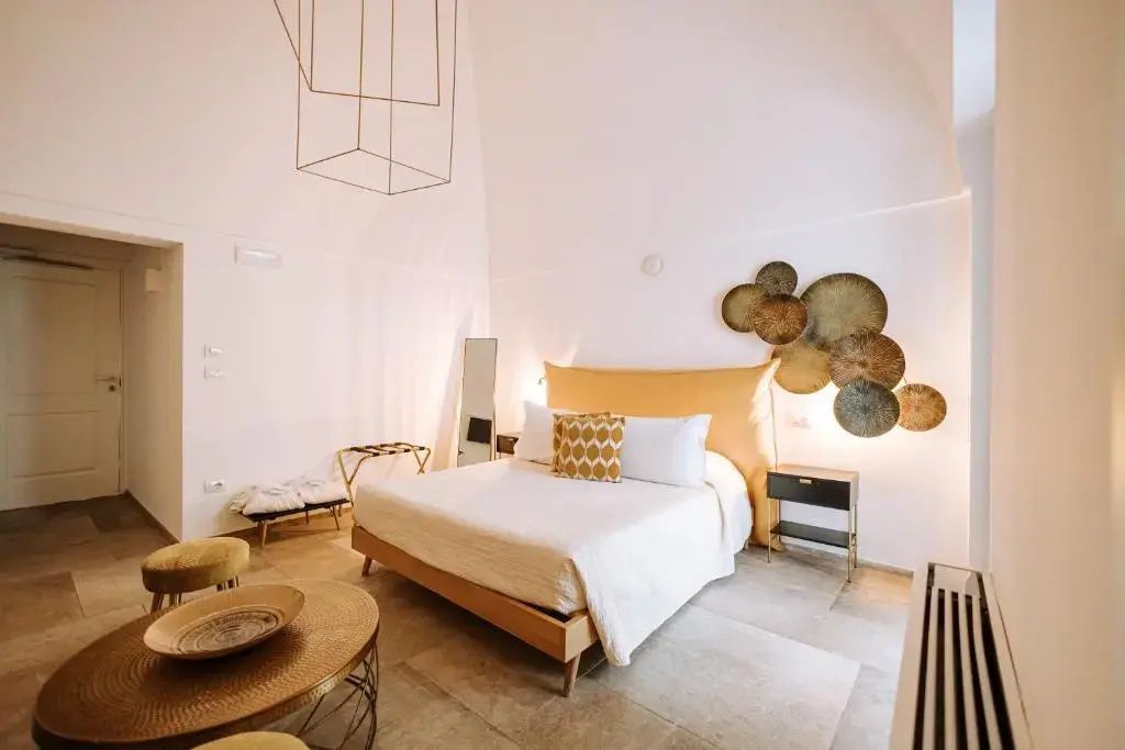 Hell eingerichtetes Hotelzimmer mit Doppelbett, gelbem Kopfteil und Wanddekoration.