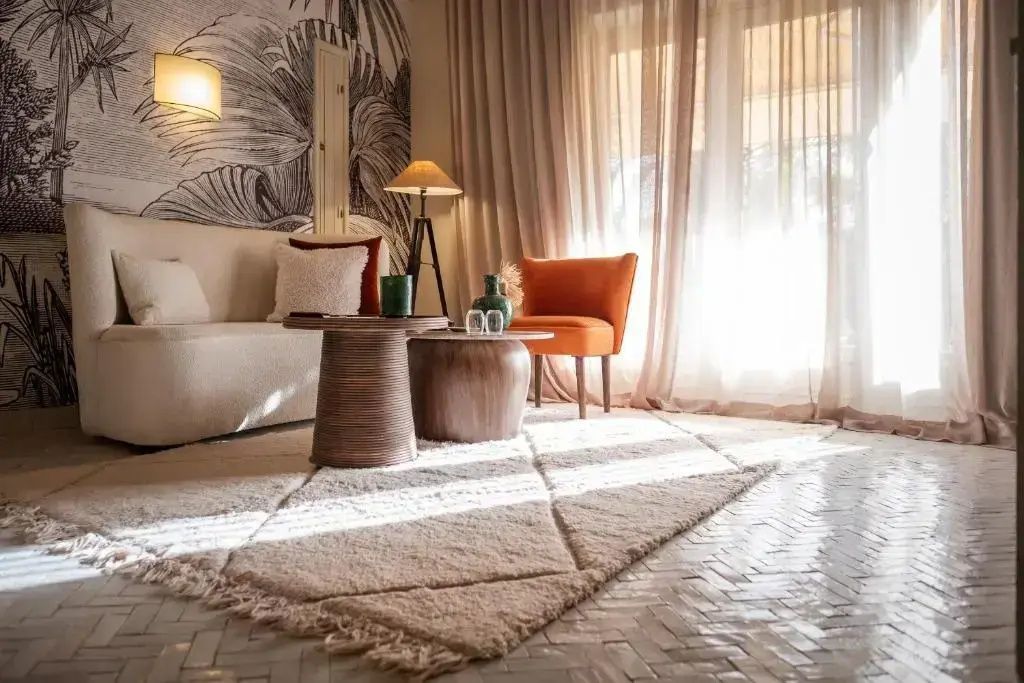 Wohnbereich mit weißem Sofa, orangefarbenem Sessel und hellem Teppich.
