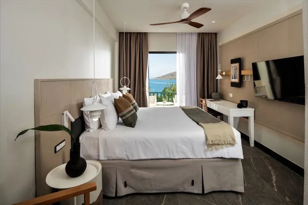 Modernes Hotelzimmer mit Doppelbett, Deckenventilator und Meerblick vom Balkon.