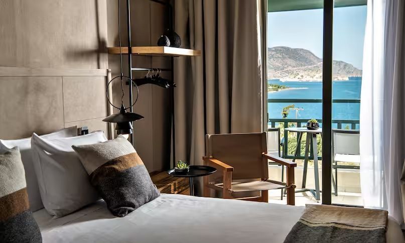 Sessel und Tisch im Zimmer mit Blick vom Balkon auf das Meer.