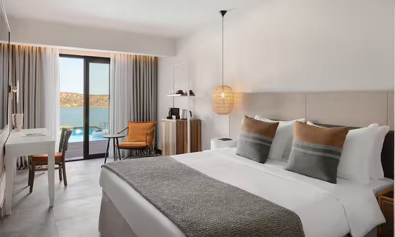 Doppelbett im Hotelzimmer mit Sitzecke, Minibar und Terrassentür.