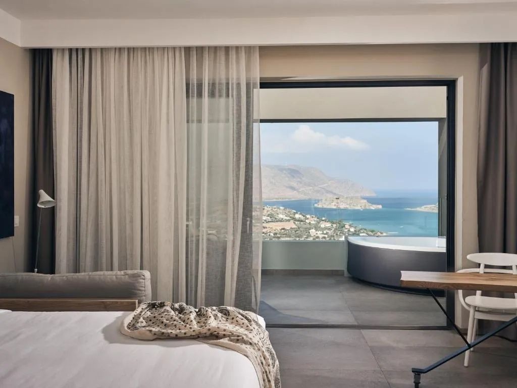 Blick aus dem Hotelzimmer auf die Terrasse mit Jacuzzi und das Meer in der Bucht.