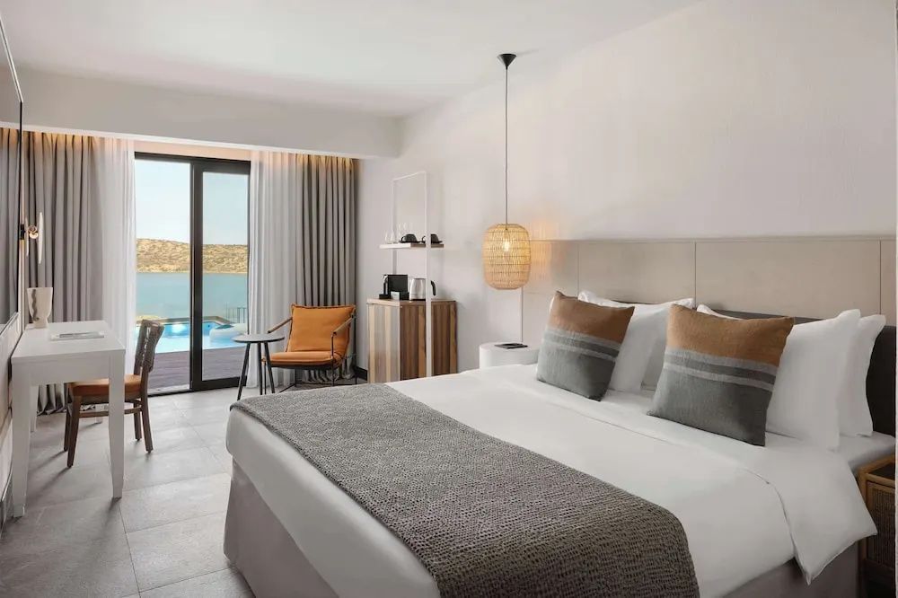 Hotelzimmer mit Doppelbett, Sessel und Zugang zur Terrasse mit privatem Pool.