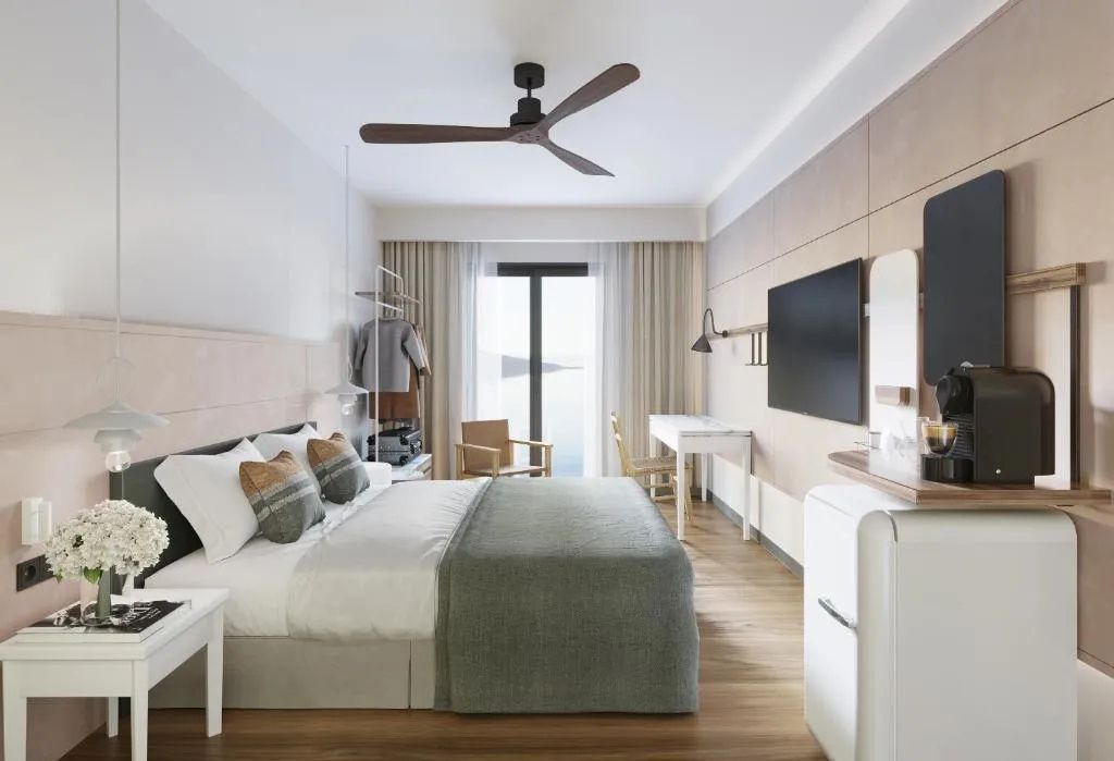 Helles Schlafzimmer mit Deckenventilator, Fernseher an der Wand und Schreibtisch.