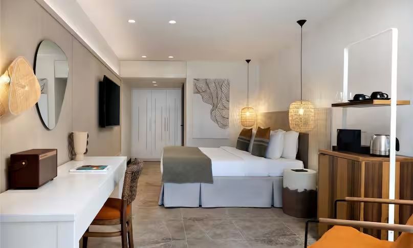 Geräumiges Hotelzimmer mit Doppelbett, Schreibtisch und Hängelampen.