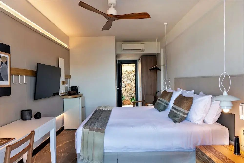 Gemütliches Hotelzimmer mit Deckenventilator, Flachbild TV und großem Doppelbett.