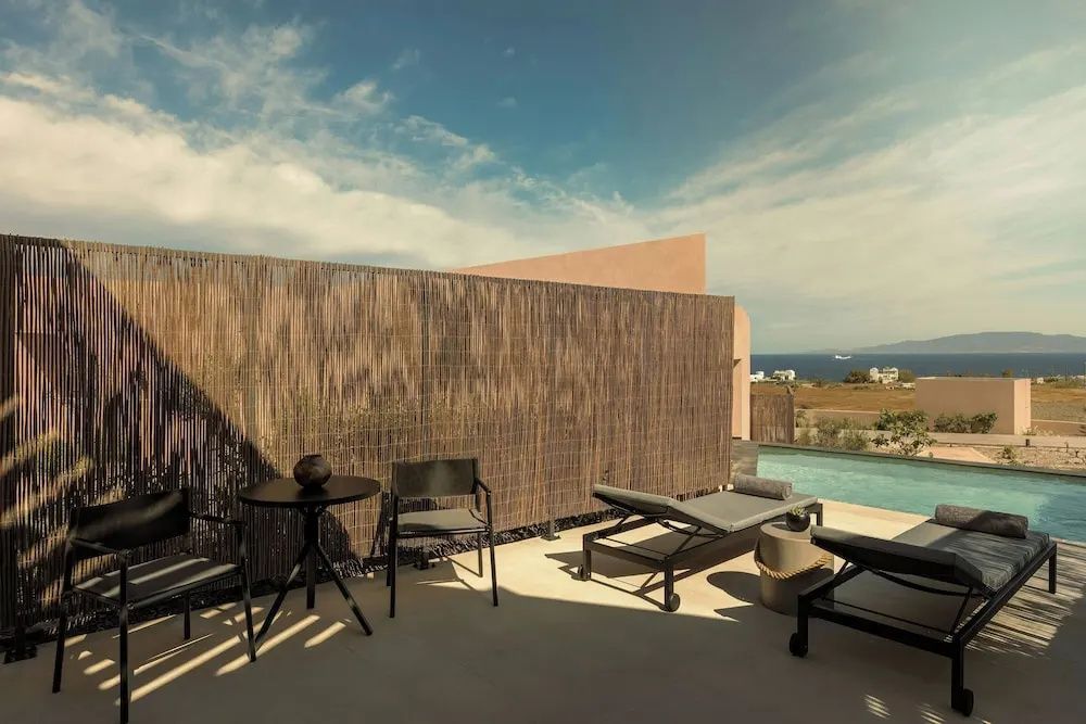 Terrasse mit Sonnenliegen, Sichtschutzwand und Ausblick auf das Meer im Hintergrund.