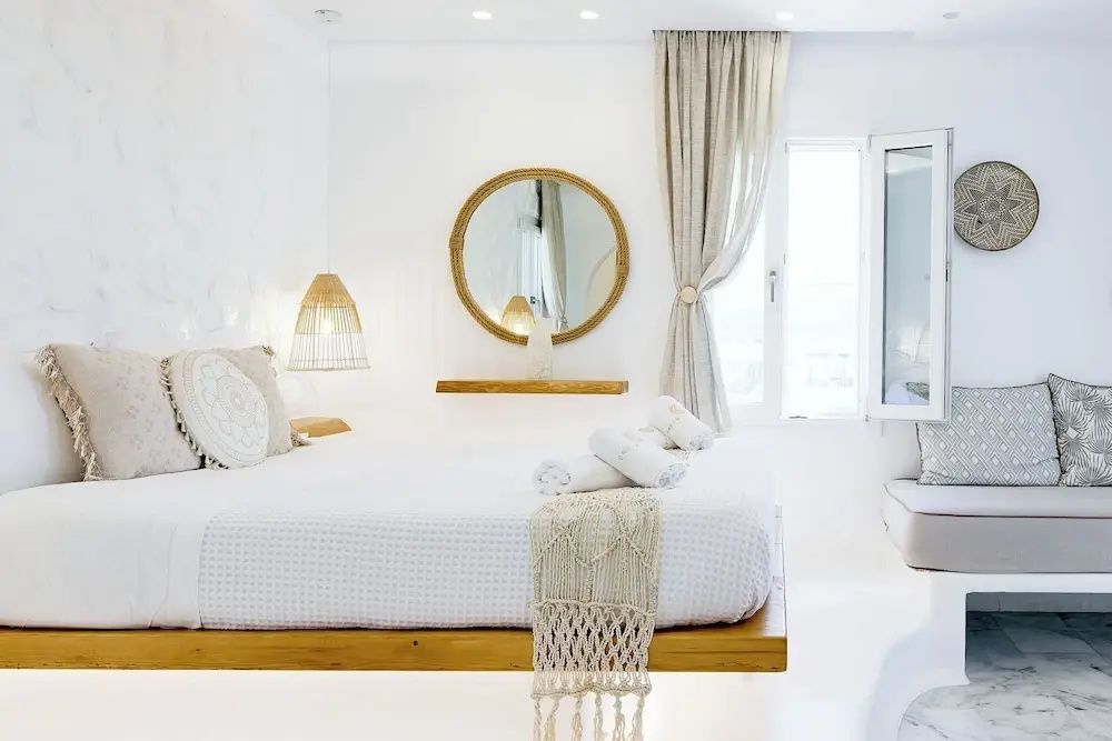 Helles Schlafzimmer mit Holzdoppelbett, rundem Spiegel und Dekoration im Boho-Stil.