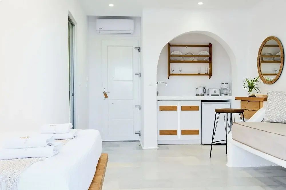 Hell eingerichtetes Zimmer mit Kitchenette in einer Rundbogenecke und Barhocker.