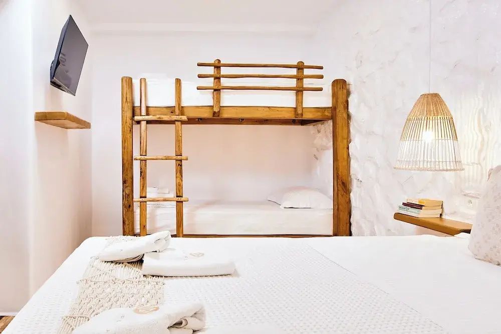Ein Doppelstockbett aus Holz in einem hell eingerichteten Hotelzimmer mit weißen Wänden.