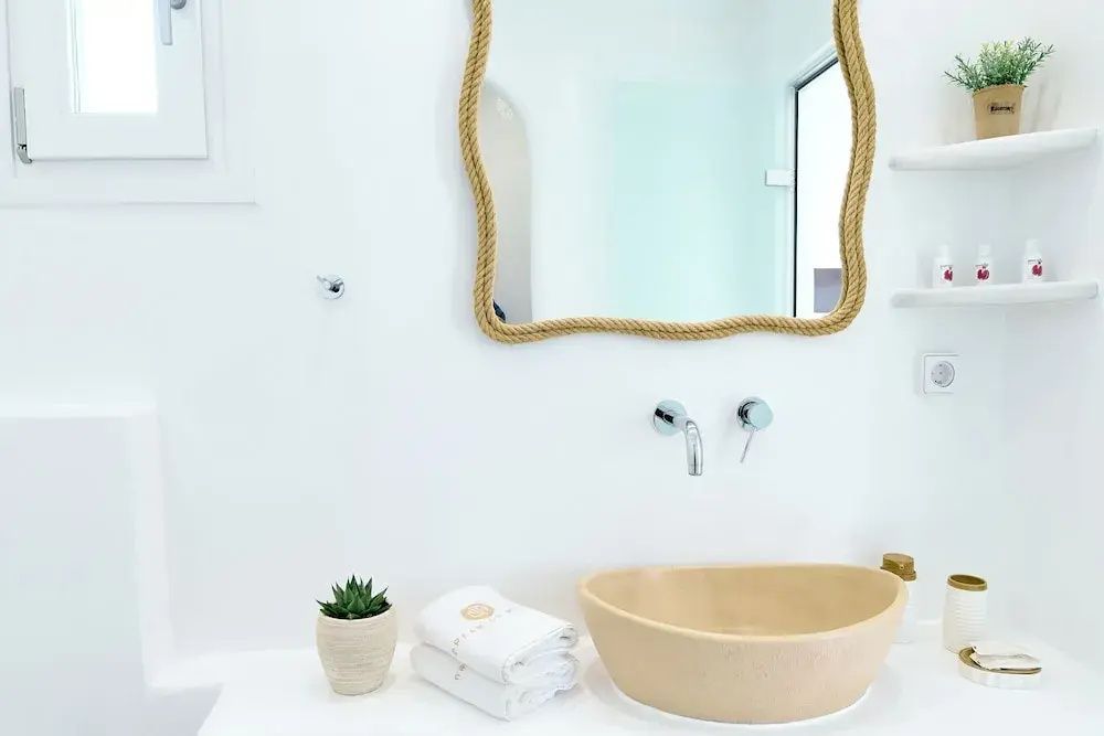 Beiges Waschbecken mit seilumrahmtem Spiegel und Handtüchern im Badezimmer.