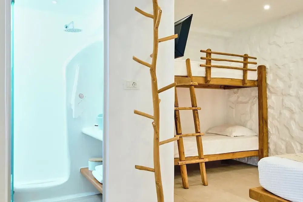 Blick in ein helles Zimmer mit einem Kleiderständer aus Astholz und angrenzendem Bad.