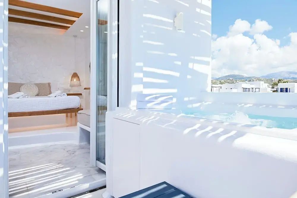 Whirlpool auf einer sonnigen Terrasse direkt neben der geöffneten Balkontür zum Zimmer.