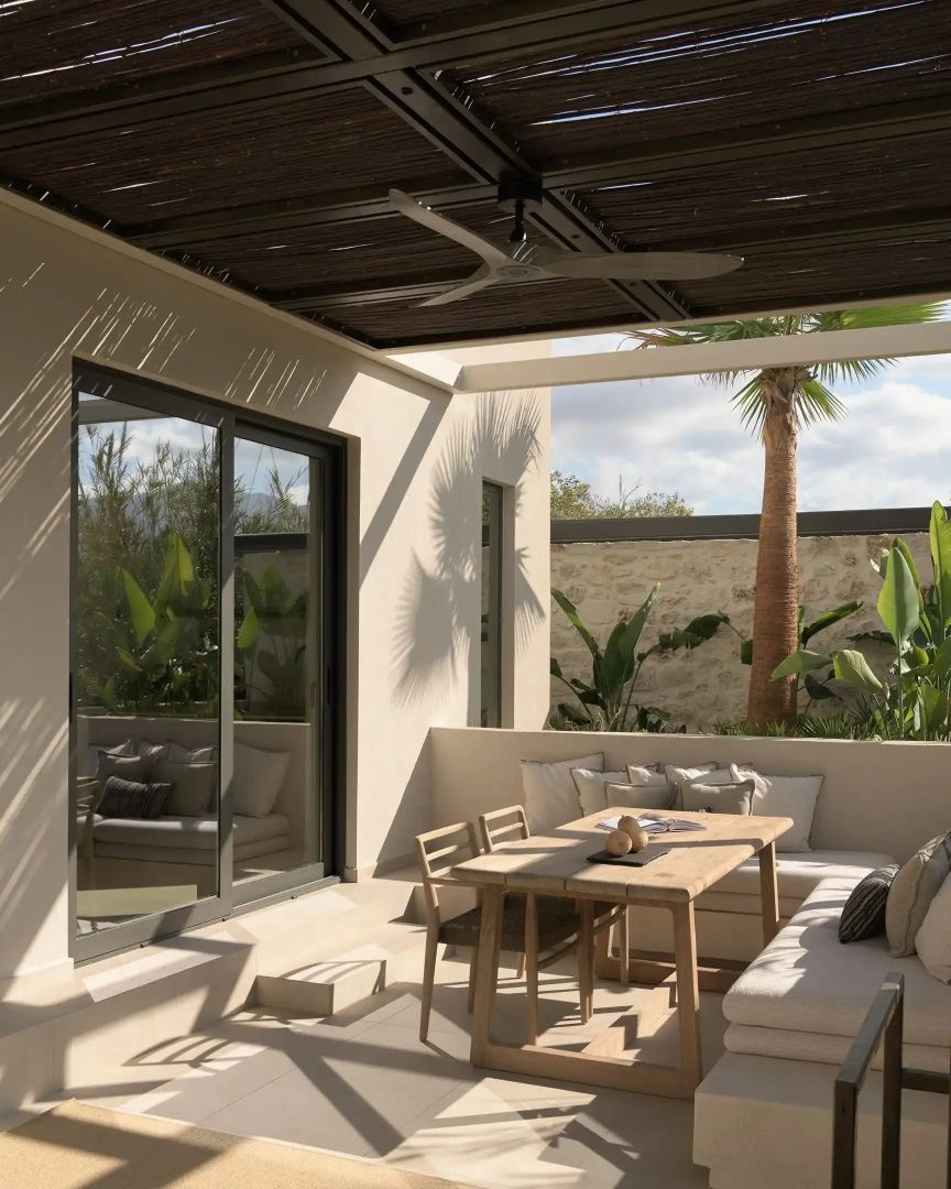 Überdachte Terrasse mit Holztisch, gepolsterten Sitzgelegenheiten und einem Deckenventilator.