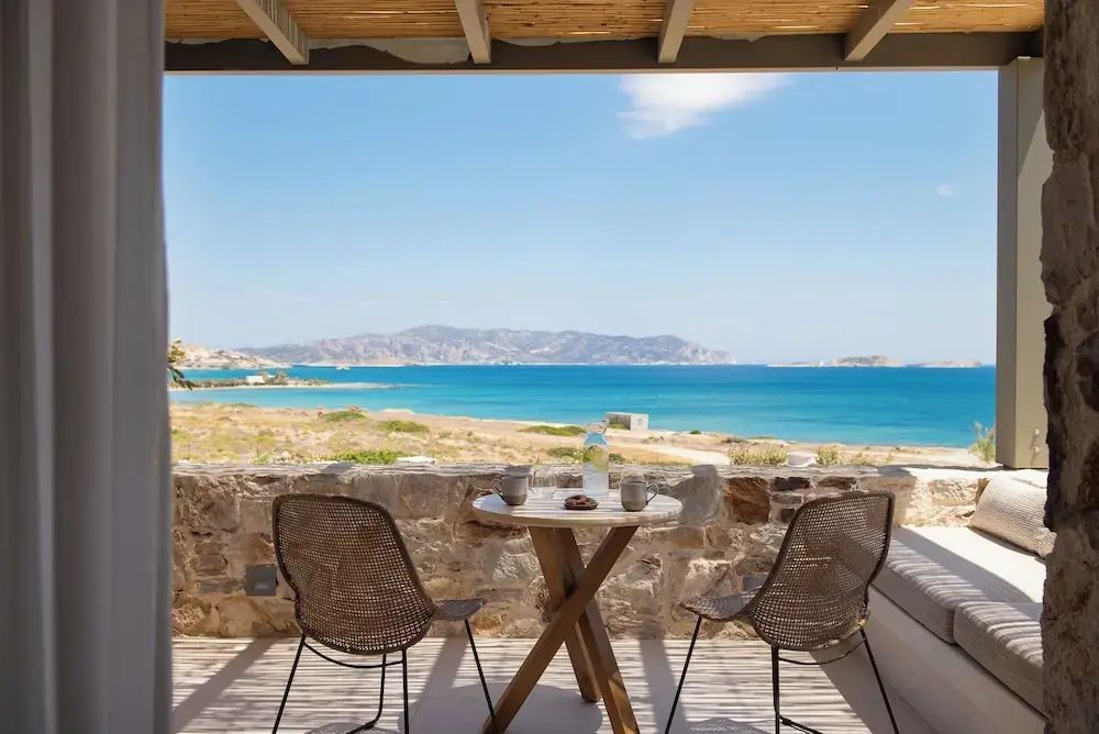 Terrasse mit zwei Stühlen und einem Tisch sowie freiem Blick auf das blaue Meer.
