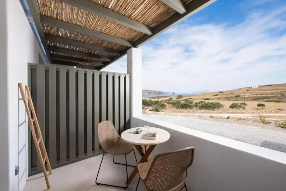 Überdachte Terrasse mit Tisch, Stühlen und freiem Blick auf die umliegende Landschaft und das Meer.