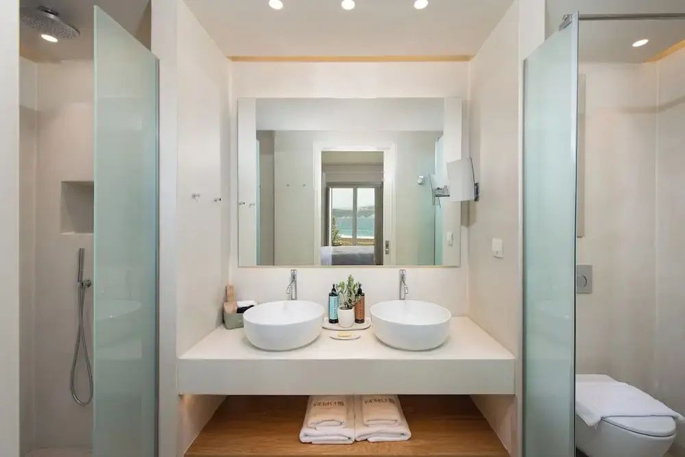 Badezimmer mit zwei runden Aufsatzwaschbecken, einem großen Wandspiegel und Handtüchern.