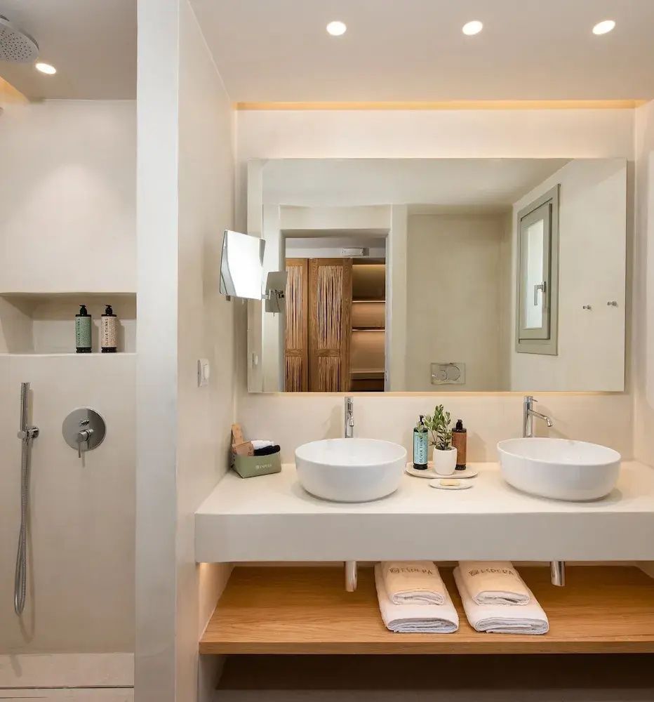 Badezimmer mit zwei weißen Aufsatzwaschbecken, großer Spiegelfläche und einer Dusche.