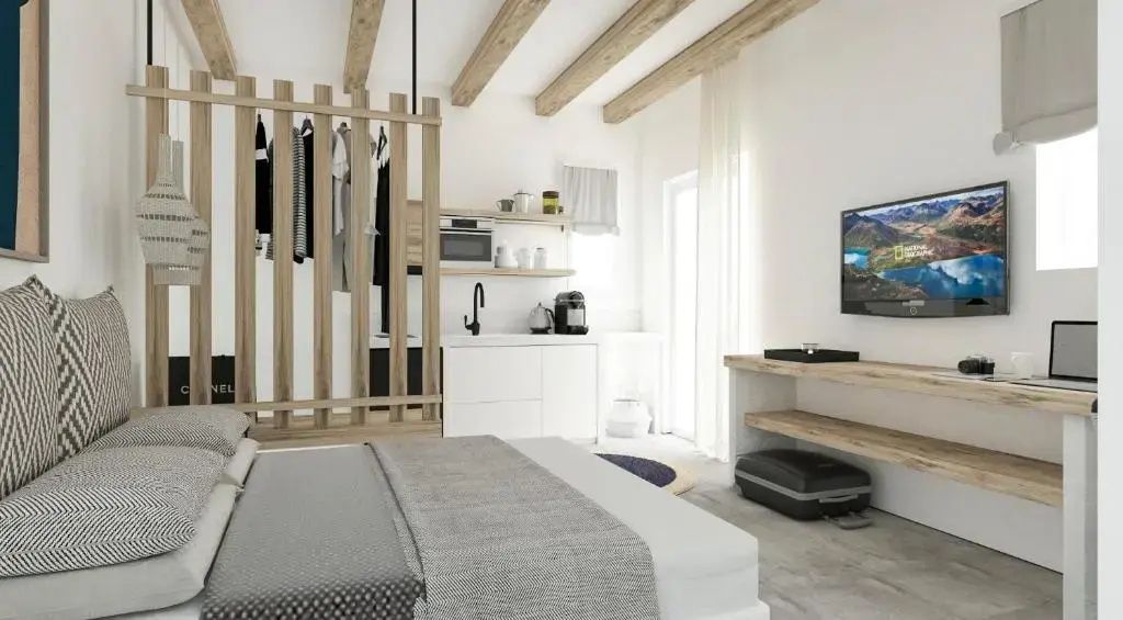 Offener Wohn- und Schlafbereich mit Kochenecke, Holztrennwand und Sichtbalken an der Decke.