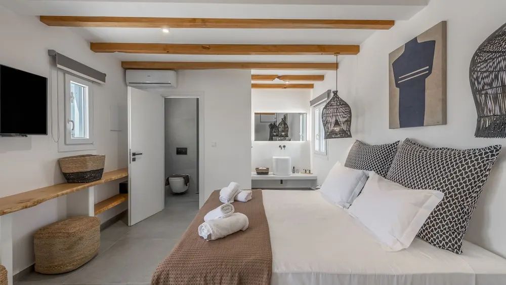 Blick durch das Schlafzimmer auf das dahinterliegende Badezimmer mit Waschbecken.