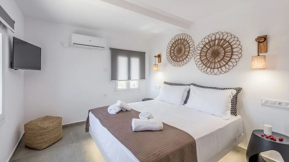 Helles Schlafzimmer mit Doppelbett, Klimaanlage und zwei rund gewebten Wanddekorationen