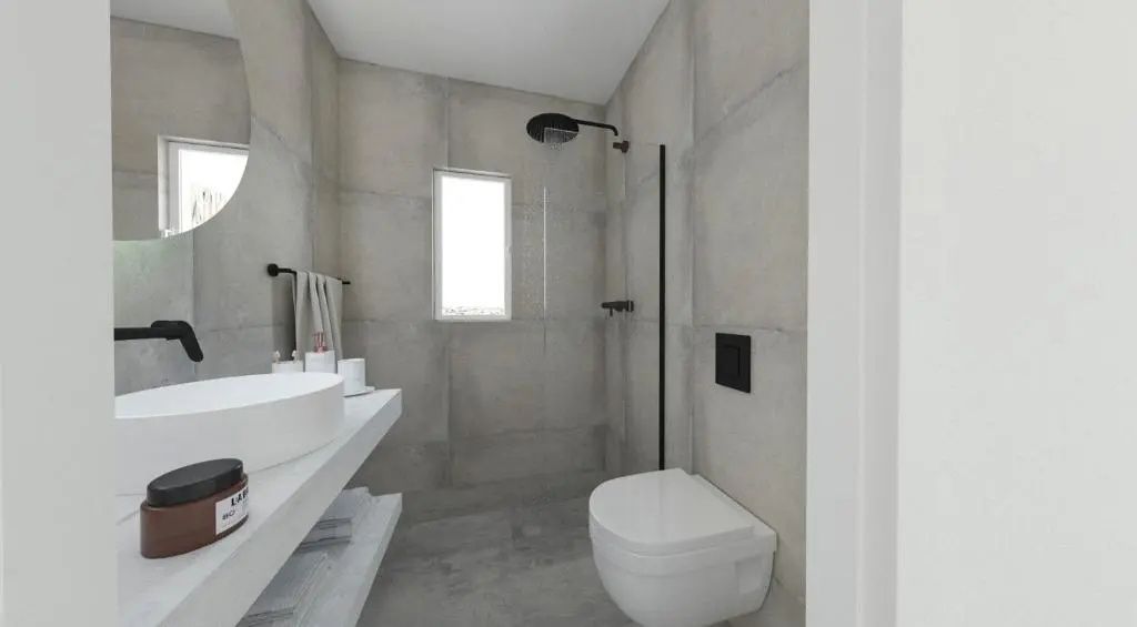 Badezimmer in Betonoptik mit ebenerdiger Dusche, weißer Toilette und schwarzer Armatur.