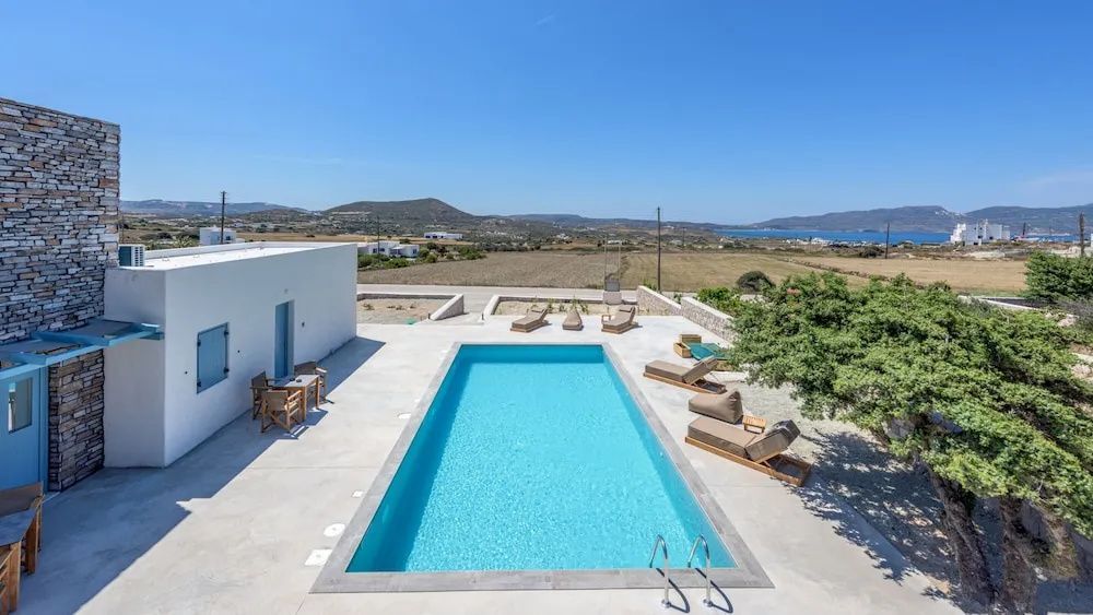 Rechteckiger Pool mit Sonnenliegen auf der Terrasse und Blick in die Landschaft.