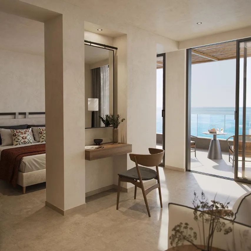 Modernes Hotelzimmer mit Doppelbett, Frisiertisch und Zugang zum Balkon mit Meerblick.