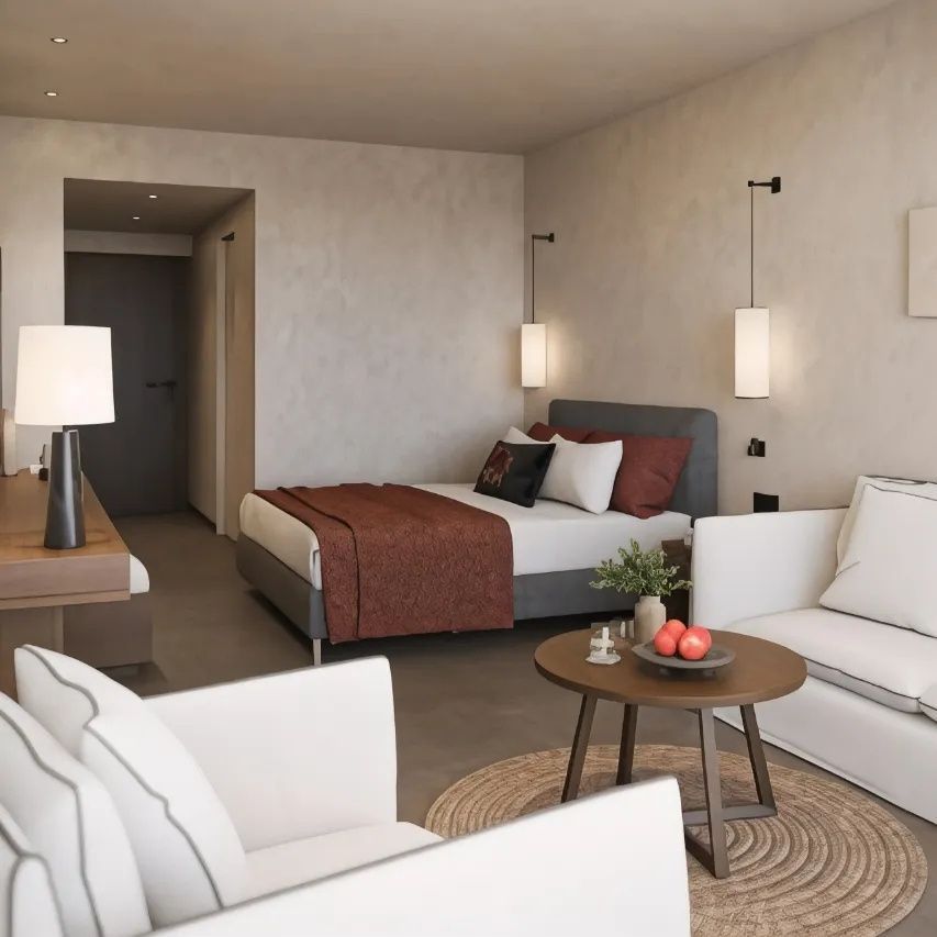 Hell eingerichtetes Hotelzimmer mit Doppelbett, weißem Sofa und rundem Holztisch.