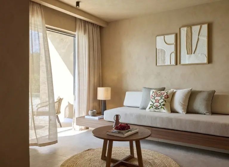 Heller Wohnbereich im Zimmer mit Sofa, rundem Teppich und Ausblick auf die Terrasse.
