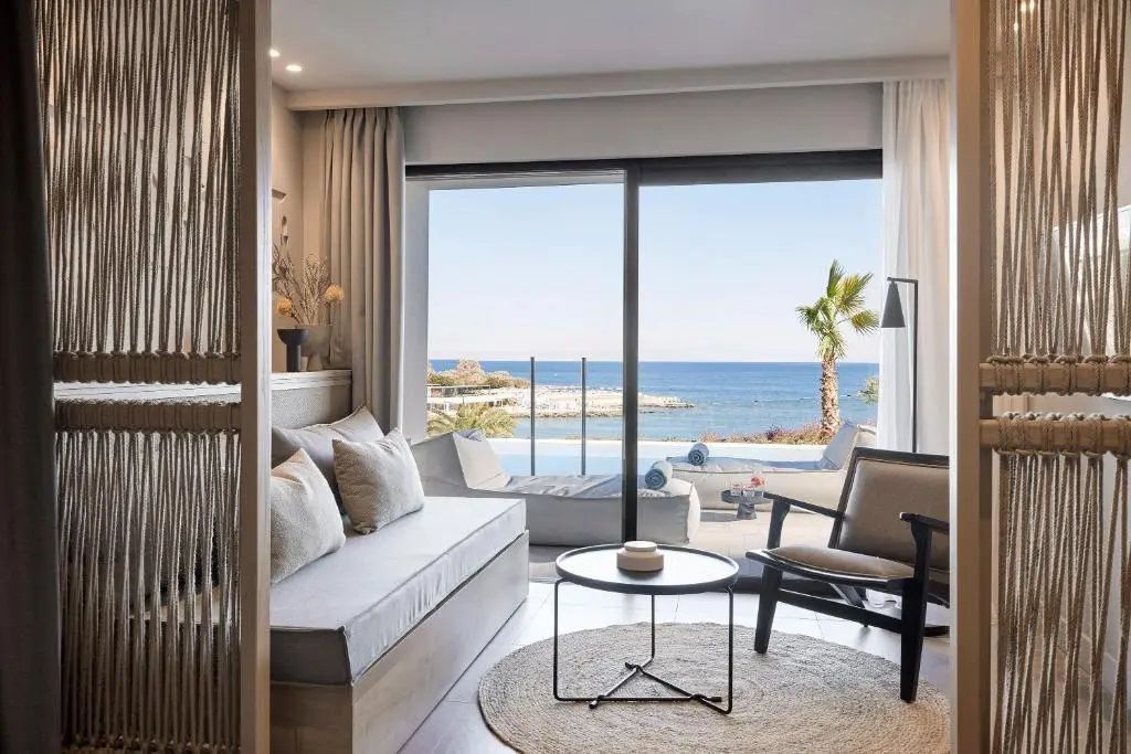 Sitzbereich im Zimmer mit Sofa und Blick durch die Glasfront auf das Meer.