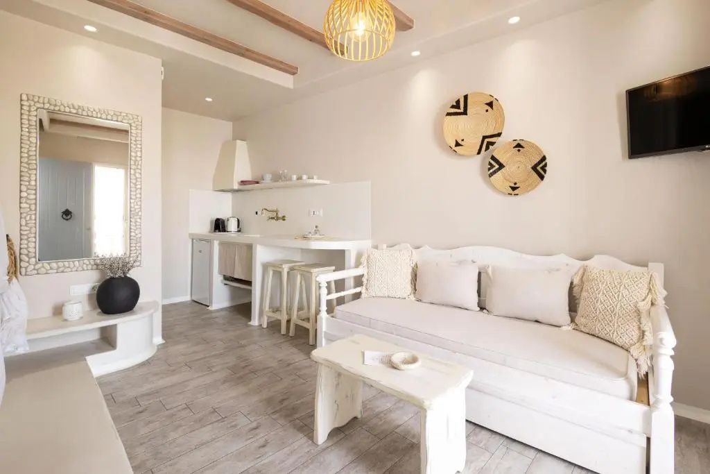 Wohnraum mit weißem Sofa, Holztisch und kleiner Küchenzeile im Hintergrund
