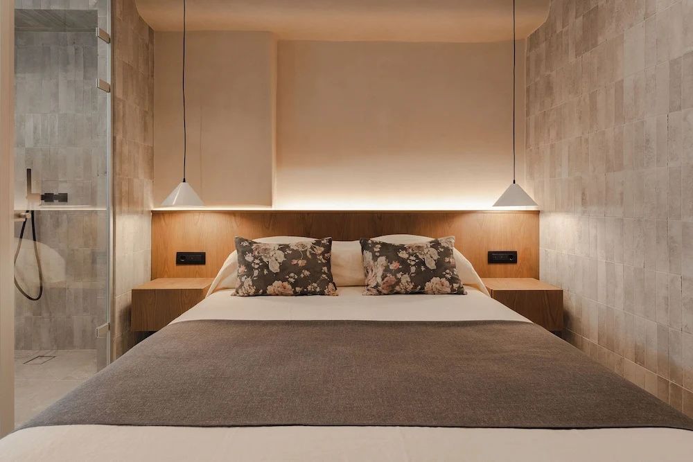 Doppelbett mit floralen Kissen und indirekt beleuchtetem Kopfteil aus Holz