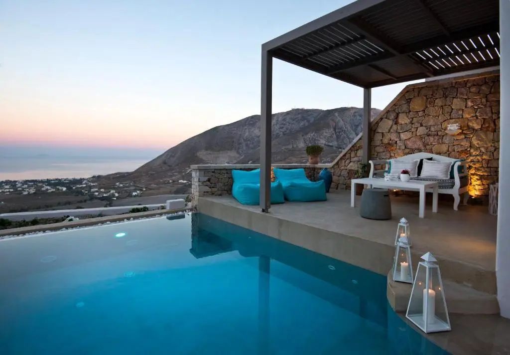 Aussenpool auf einer Terrasse mit Sitzgelegenheiten, Überdachung und Blick auf Berge und Meer bei Dämmerung.