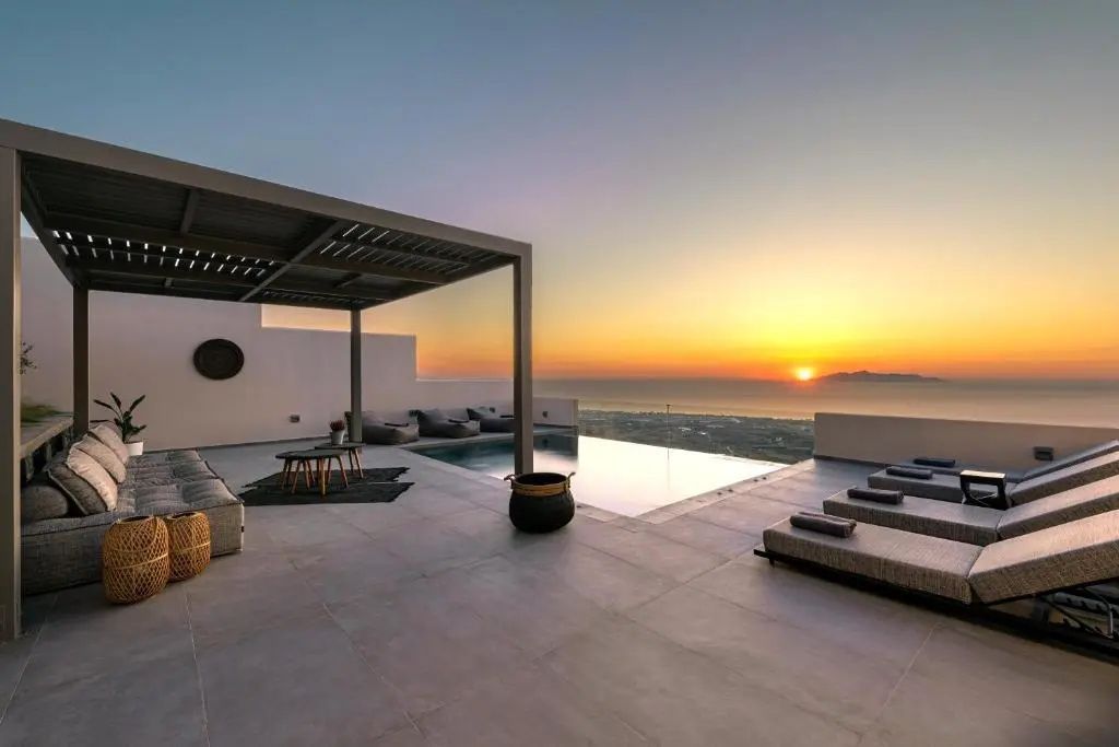 Terrasse mit Pool, Pergola und Sonnenliegen bei Sonnenuntergang über dem Meer.