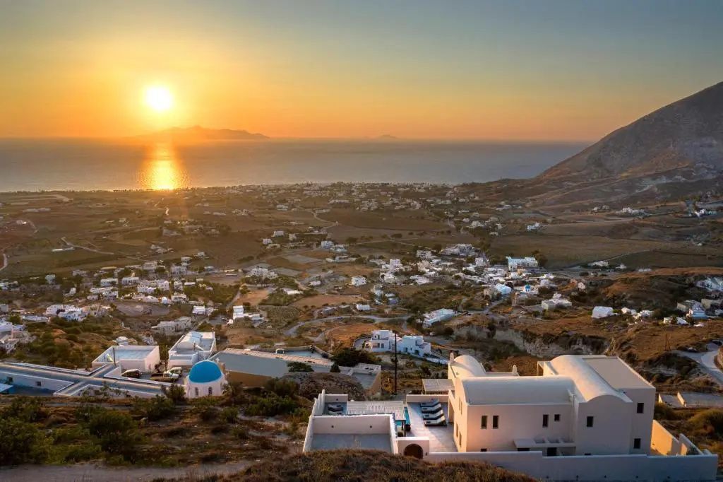 Panoramablick über weiße Häuser und die Küste bei Sonnenuntergang am Meer.