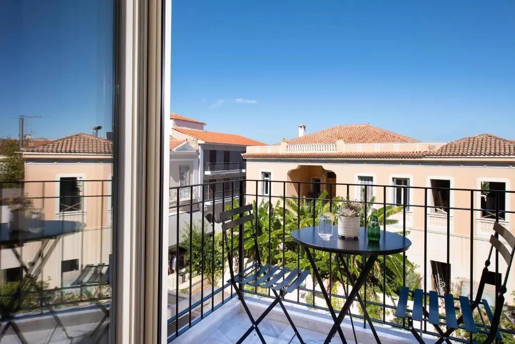Blick vom Balkon auf einen kleinen Tisch mit Stühlen und nahegelegene Gebäude.