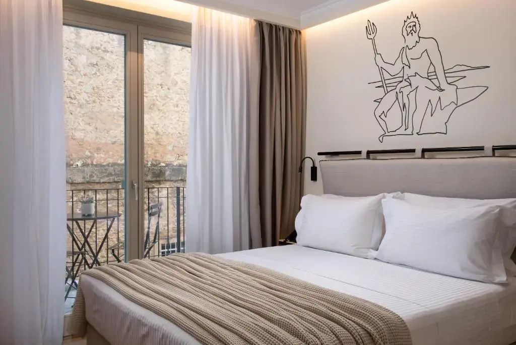 Schlafzimmer mit großem Doppelbett und tiefen Fenstern zum Balkon.