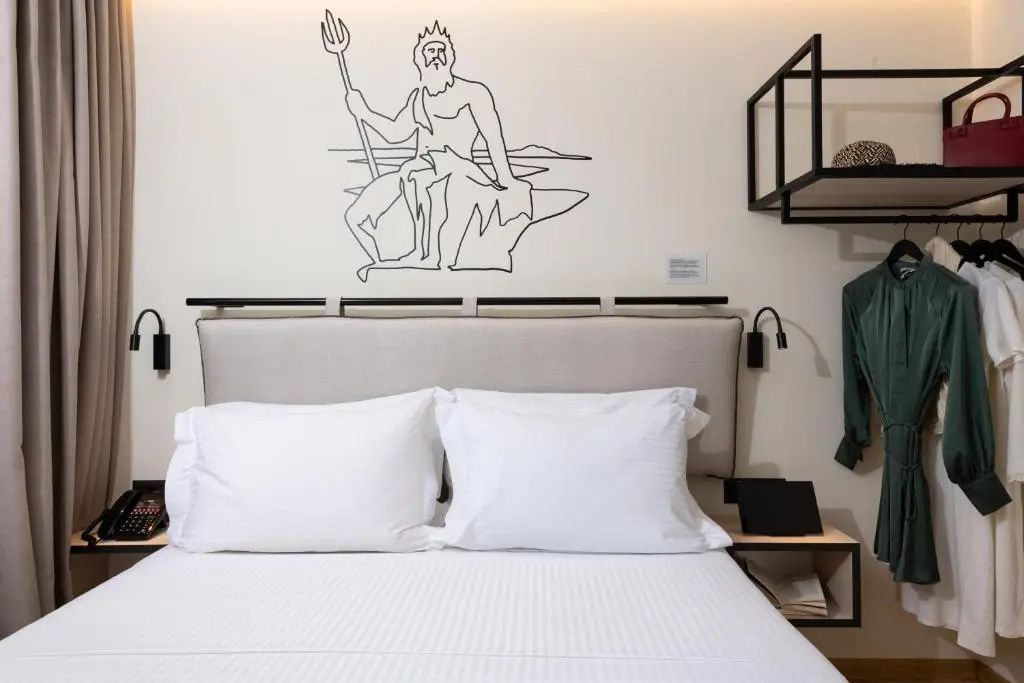 Doppelbett mit weißen Kissen und einer Wandzeichnung eines Gottes an der Kopfseite