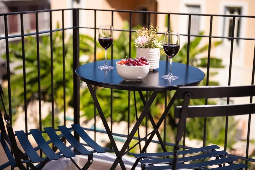 Schwarzer Tisch auf dem Balkon mit zwei Weingläsern und einer Schale Trauben.
