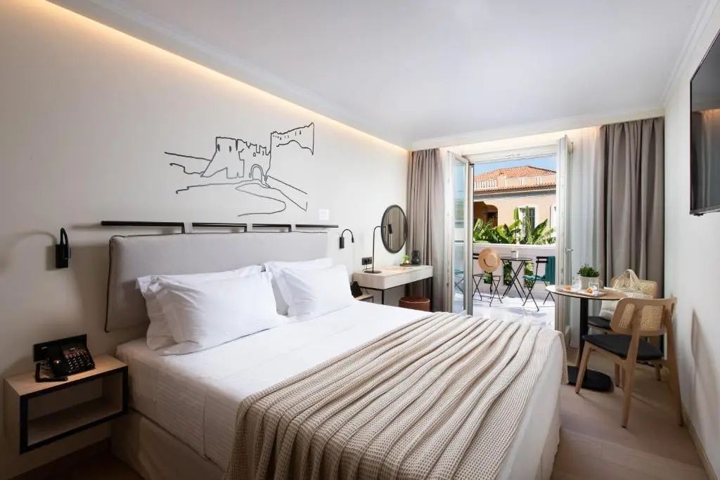 Helles Doppelzimmer mit modernem Bett, Kunst an der Wand und geöffneter Balkontür.
