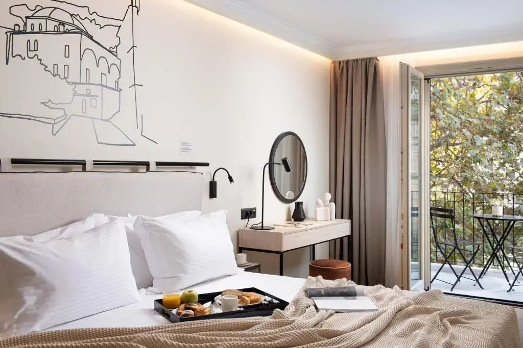 Blick auf ein Doppelbett mit Frühstückstablett und einen Schminktisch im Hotelzimmer.
