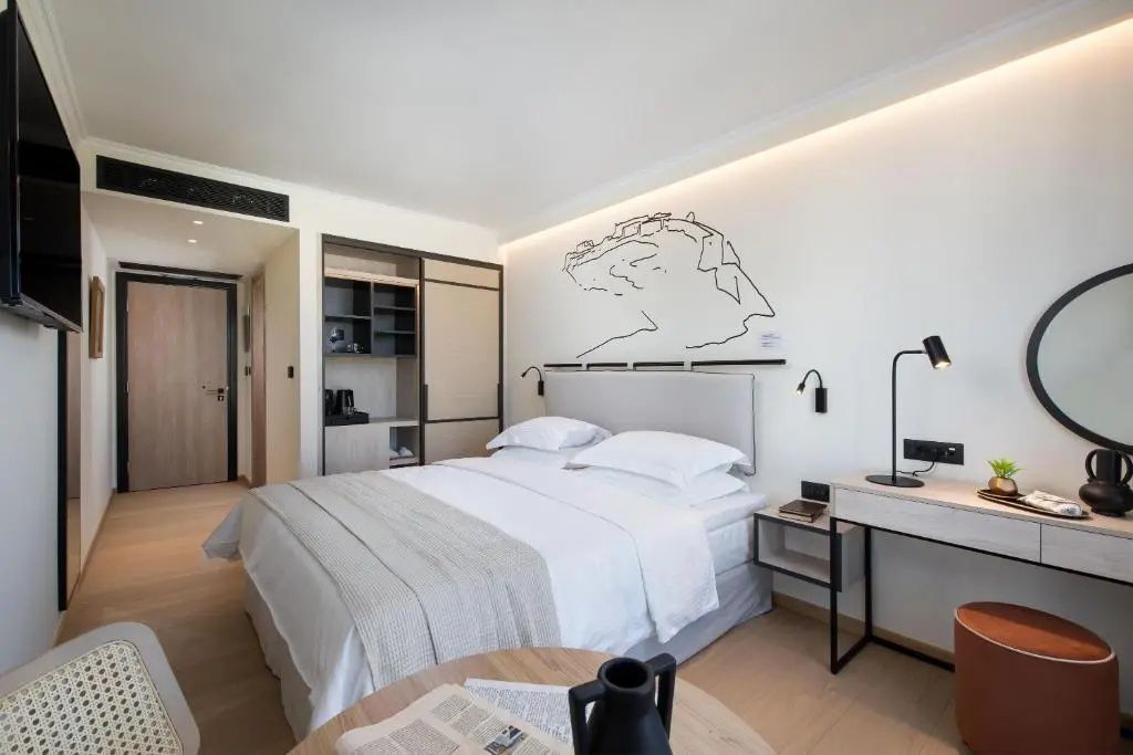 Geräumiges Hotelzimmer mit Doppelbett, hellem Holzschrank und Wandschmuck.