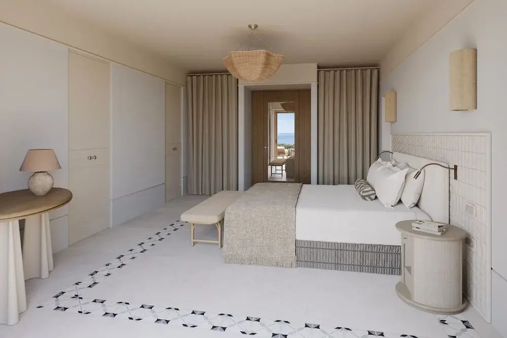 Geräumiges Schlafzimmer im Hotel mit großem Bett, heller Einrichtung und gemustertem Fliesenboden.