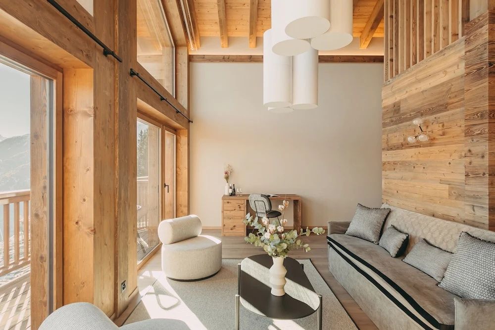Lichtdurchfluteter Wohnbereich einer Suite mit Holzverkleidung, Sofa und Schreibtisch.