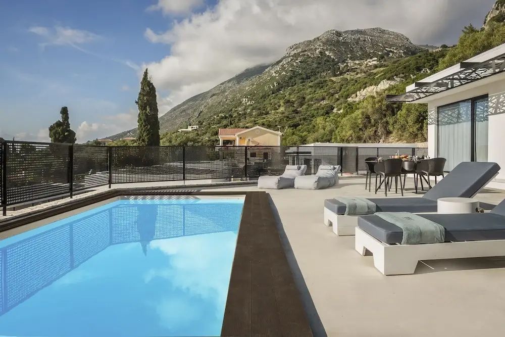 Pool auf einer Sonnenterrasse mit Liegen, Sitzbereich und Blick auf eine Berglandschaft.