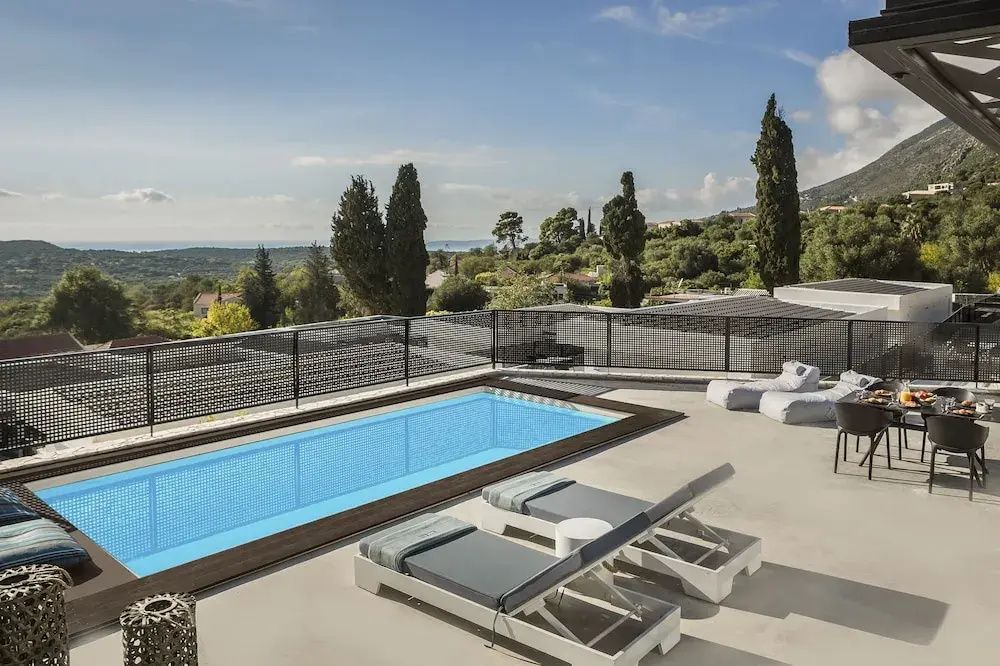 Pool auf einer Terrasse mit zwei Sonnenliegen und Blick auf die umliegenden grünen Hügel.